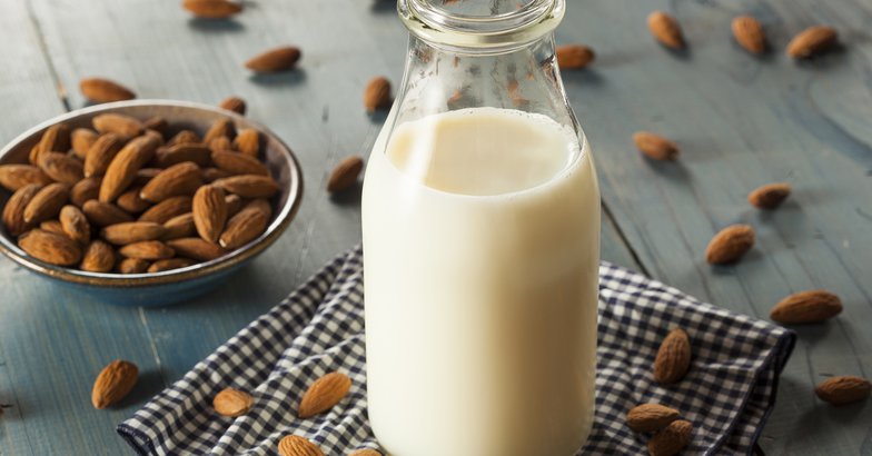 almond milk on wooden counter with almonds