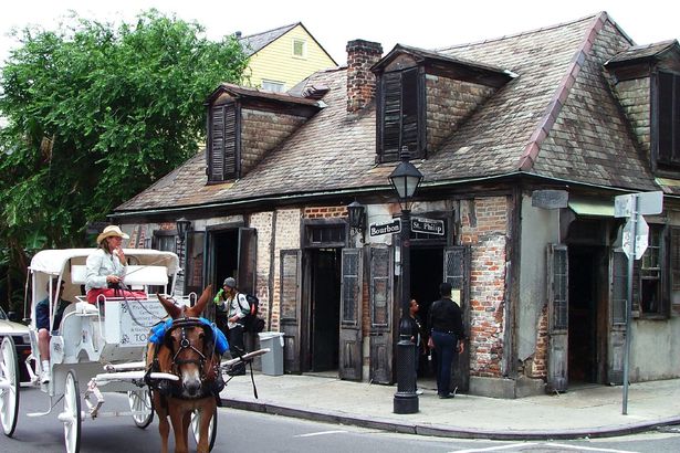 New Orleans: Tourist carriage passing "Laffitte's Blacksmith Shop" bar, uptown lake corner of Bourbon & St. Phillip Streets, French Quarter