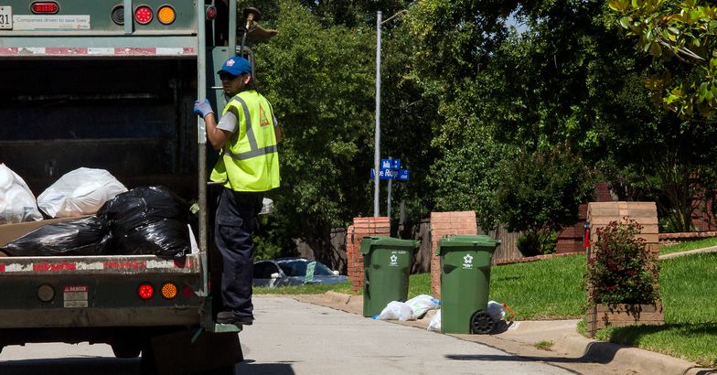 garbage truck with sanitation worker in suburbian neighborhood