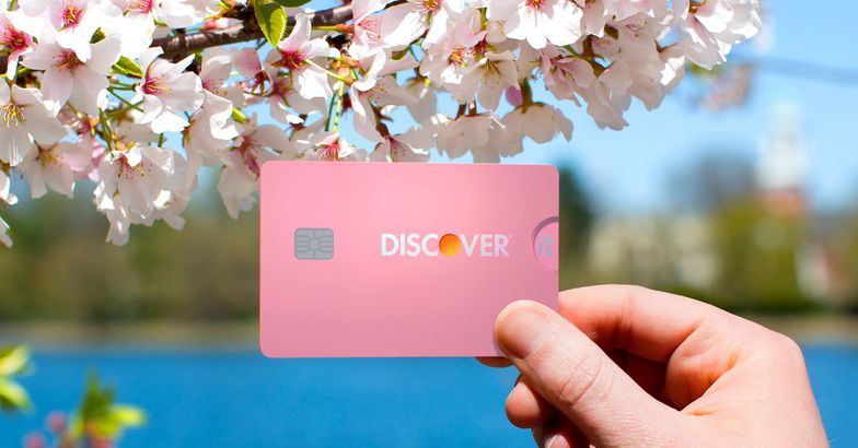 hand holding pink discover it card with pink flowers and lake in background