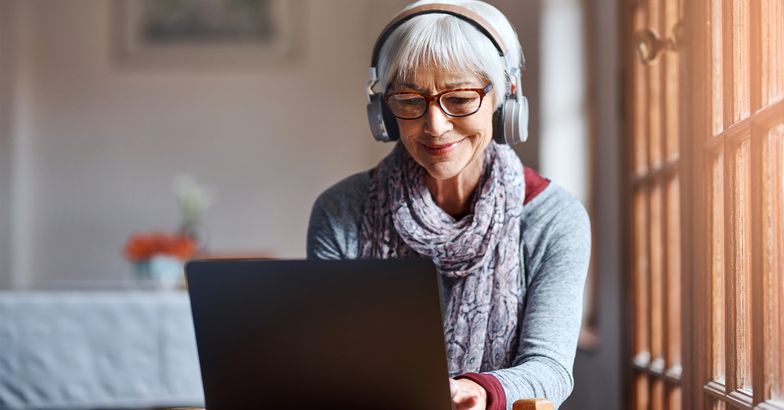 Senior woman on her laptop wearing headphones