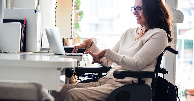Woman in a wheelchair smiling while on her computer