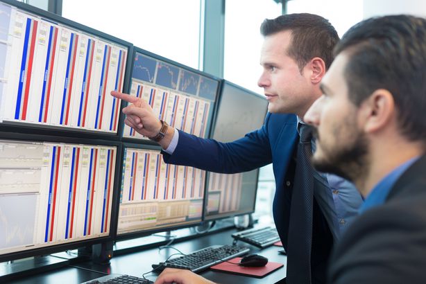 6 investment risk management strategies Stock traders looking at screens