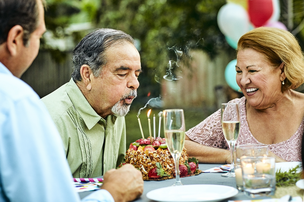 Senior woman looking at man blowing candles on birthday cake