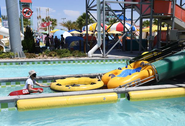 A lifeguard wearing a mask sends rafts back up an attraction for guests at Cowabunga Bay Water Park