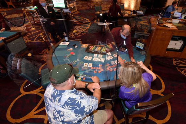 Guests play blackjack at a table installed with plexiglass safety shield dividers and only three seats for social distancing at Mandalay Bay Resort and Casino 