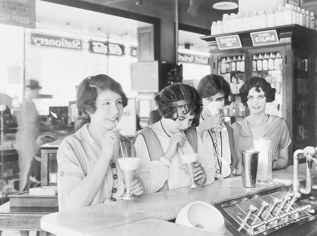 Flappers at a soda fountain drinking milk shakes in 1926.