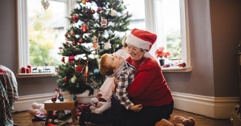 Grandma hugging child on Christmas day in front of tree