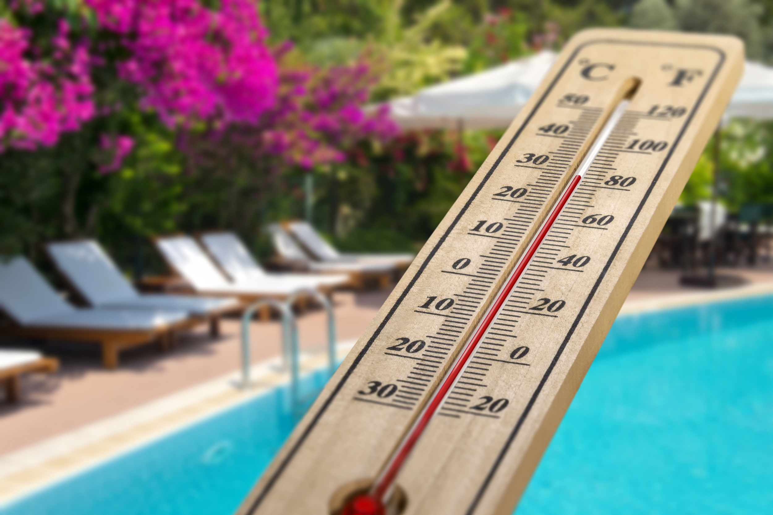 Outdoor thermometer in front a pool