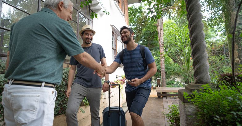 Senior man welcoming two younger men to rent his home