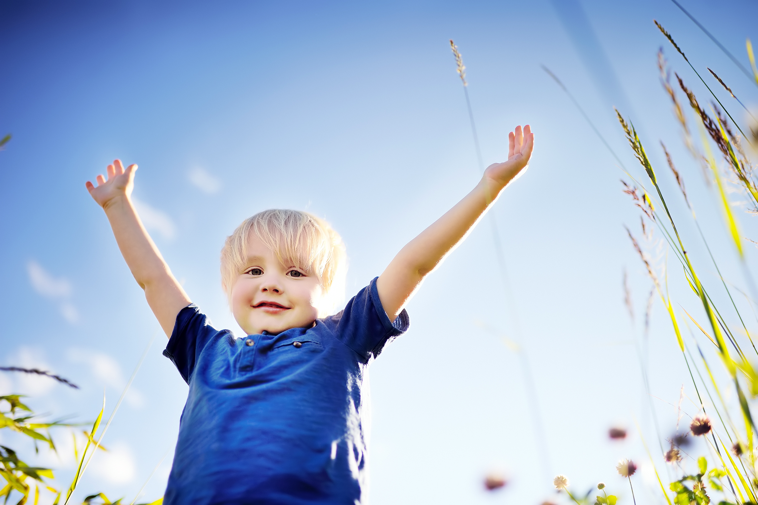 Young kid outside with his hands in the air