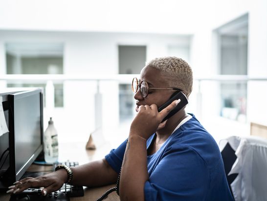 Secretary talking on telephone at hospital reception stock photo