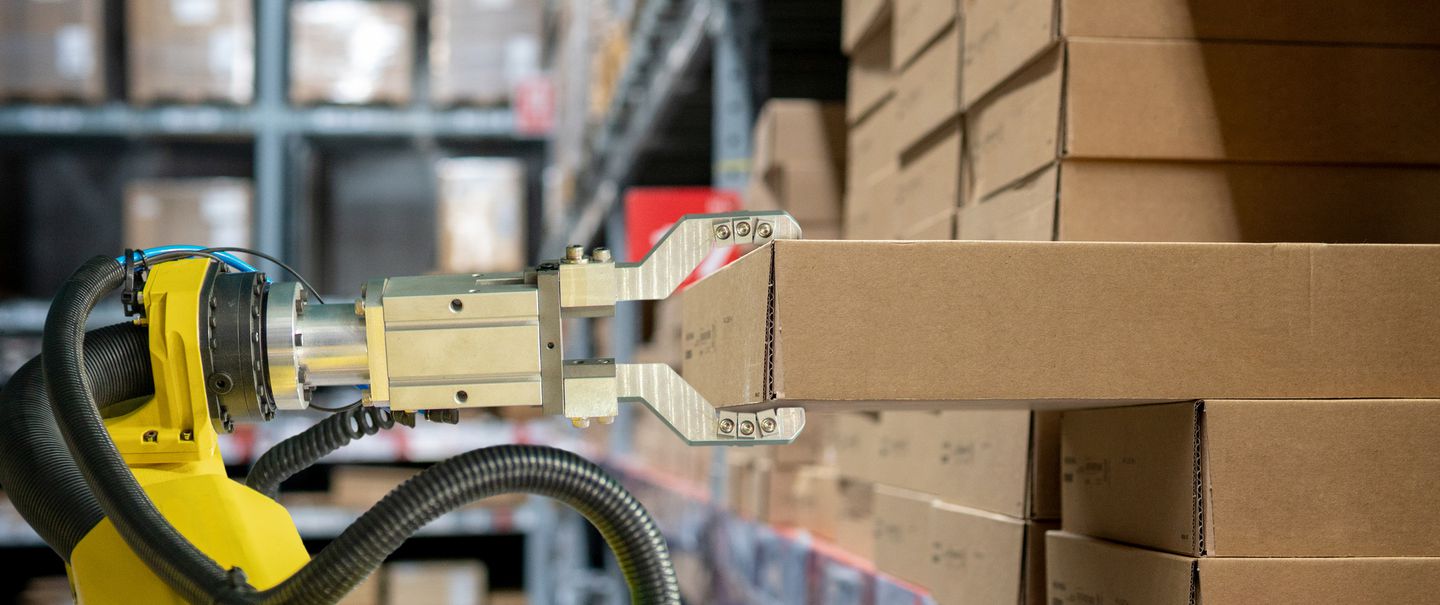 Yellow robotic arm carry cardboard box in warehouse stock photo