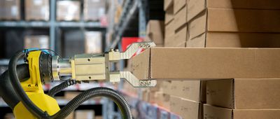 Yellow robotic arm carry cardboard box in warehouse stock photo