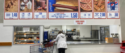 Person Getting Food At the Ordering Kiosk in a Costco, Large Photos of Items Available with Prices on the Top of the Kiosk