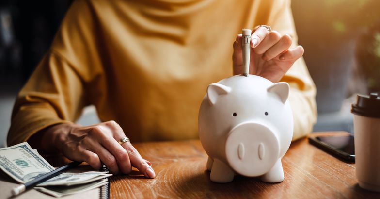 senior woman putting money in piggy bank