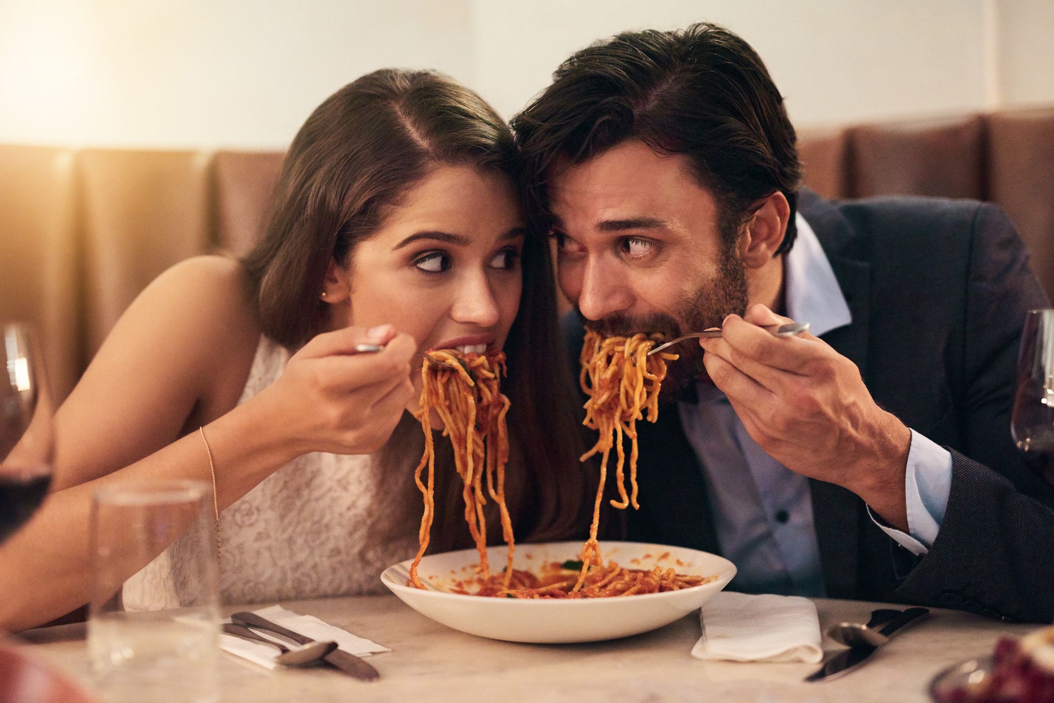 Shot of a young couple sharing a plate of spaghetti during a romantic dinner at a restaurant
