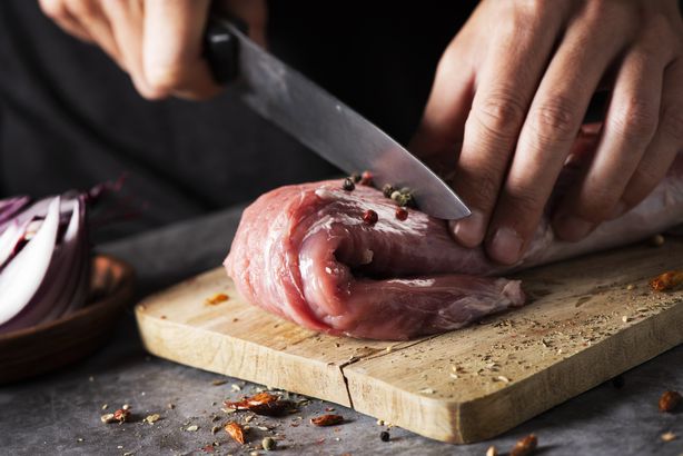 man cutting a piece of pork tenderloin