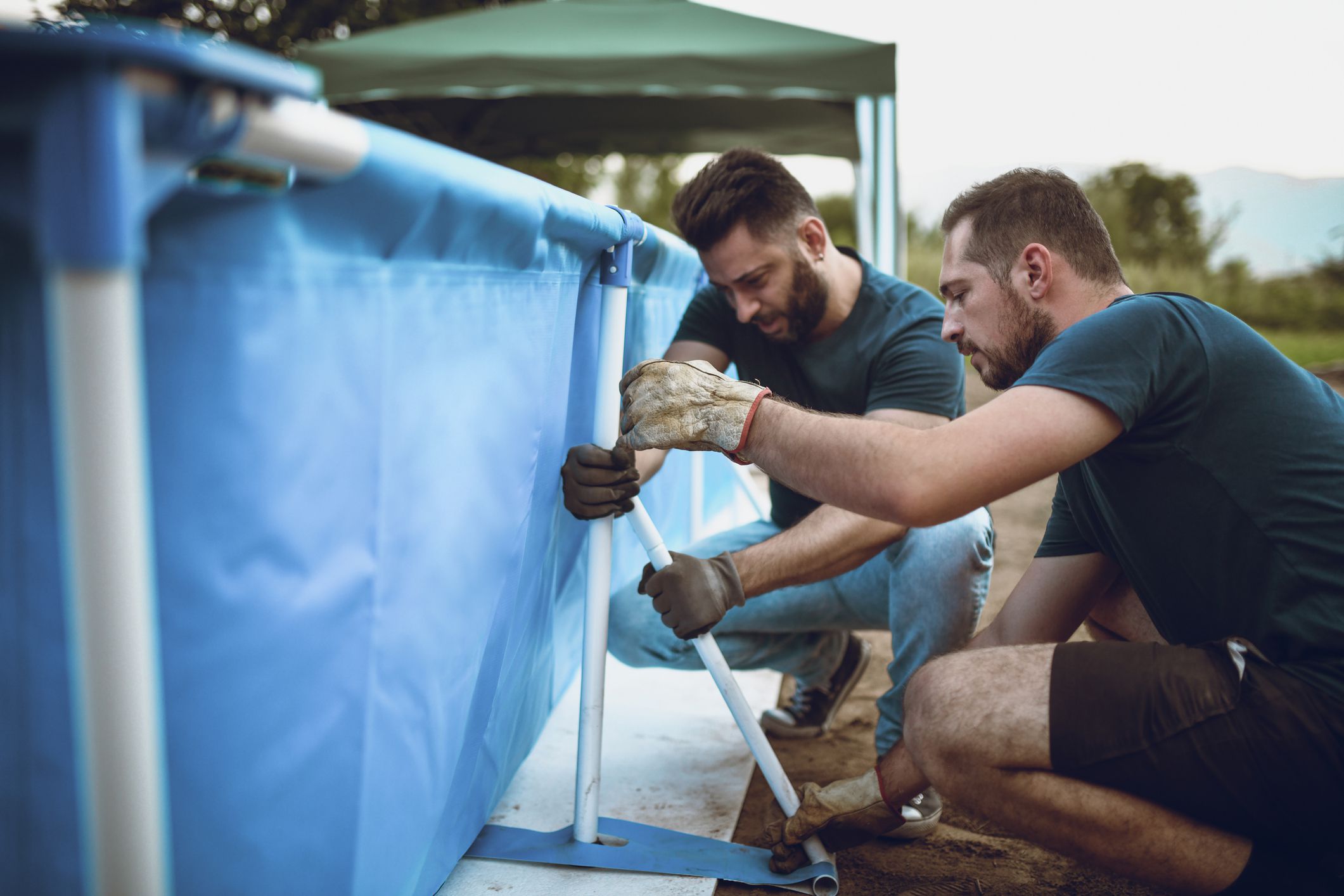 Two Male Workers Setting Up Portable Swimming Pool