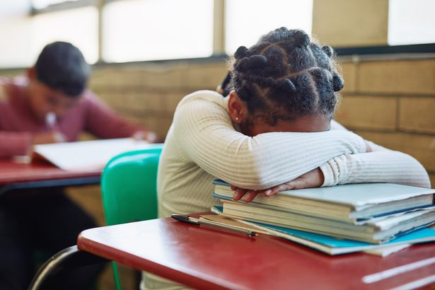 niña durmiendo en su escritorio en un aula