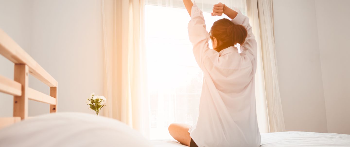 Woman stretching in bed after waking up