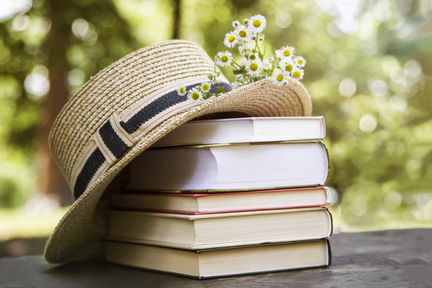 stack of books with a hat and flower