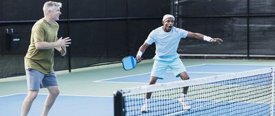 Senior men playing paddleball, hitting ball