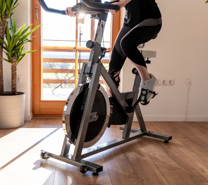 Low section view of a young woman in sportswear exercising on exercise bike at home
