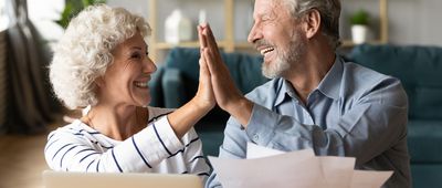Excited older couple giving high five, celebrating good news