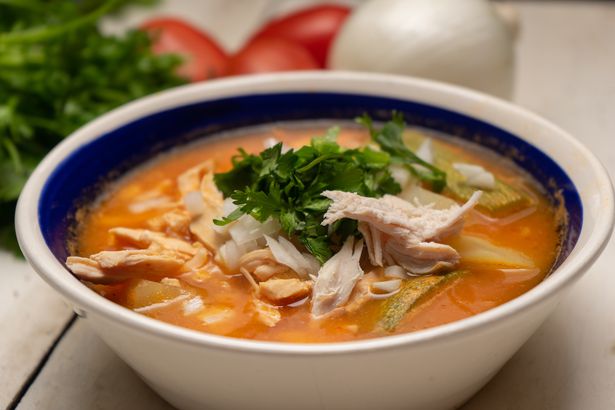 Mexican chicken soup with vegetables and rice on white background