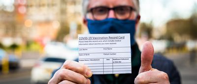 Senior man holding covid-19 vaccination record card