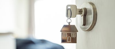 Open the door and door handle with a key and a keychain shaped house. Property investment and house mortgage financial real estate concept