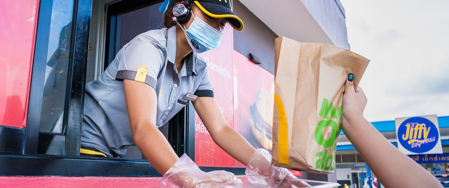 Female staff at McDonald's deliver food to customers through the door of the car at the pick up point in Bangkok, Thailand
