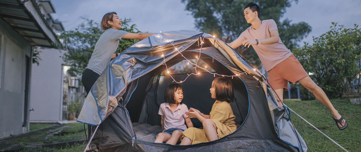 Asian chinese family putting on string light decorating camping at backyard of their house staycation weekend activities