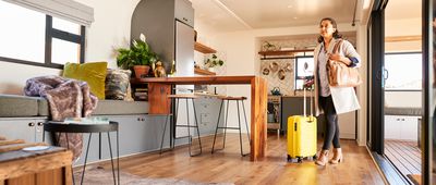 Young woman standing with a suitcase at her vacation rental