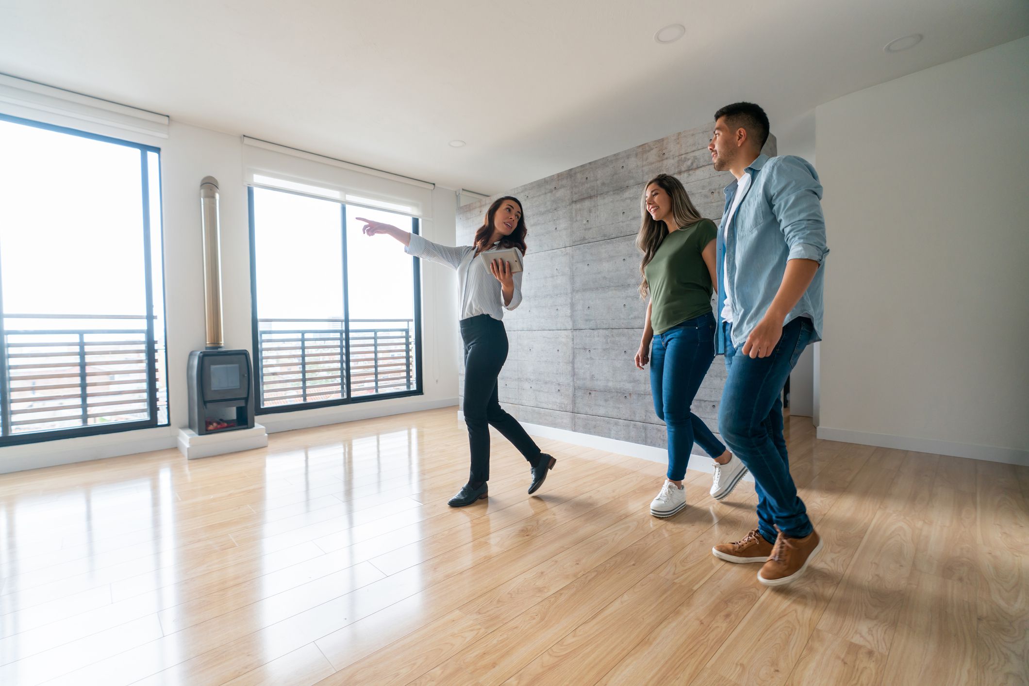 Real estate agent showing a house for sale to a happy couple  - home ownership concepts