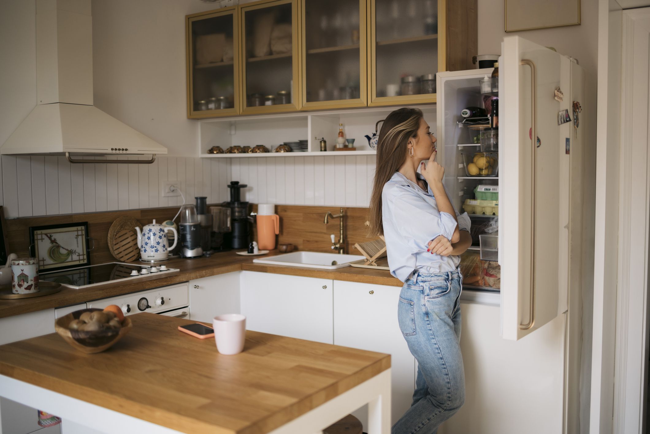 Young woman searching food inside a refrigerator at home. Caucasian female looking for food into refrigerator.