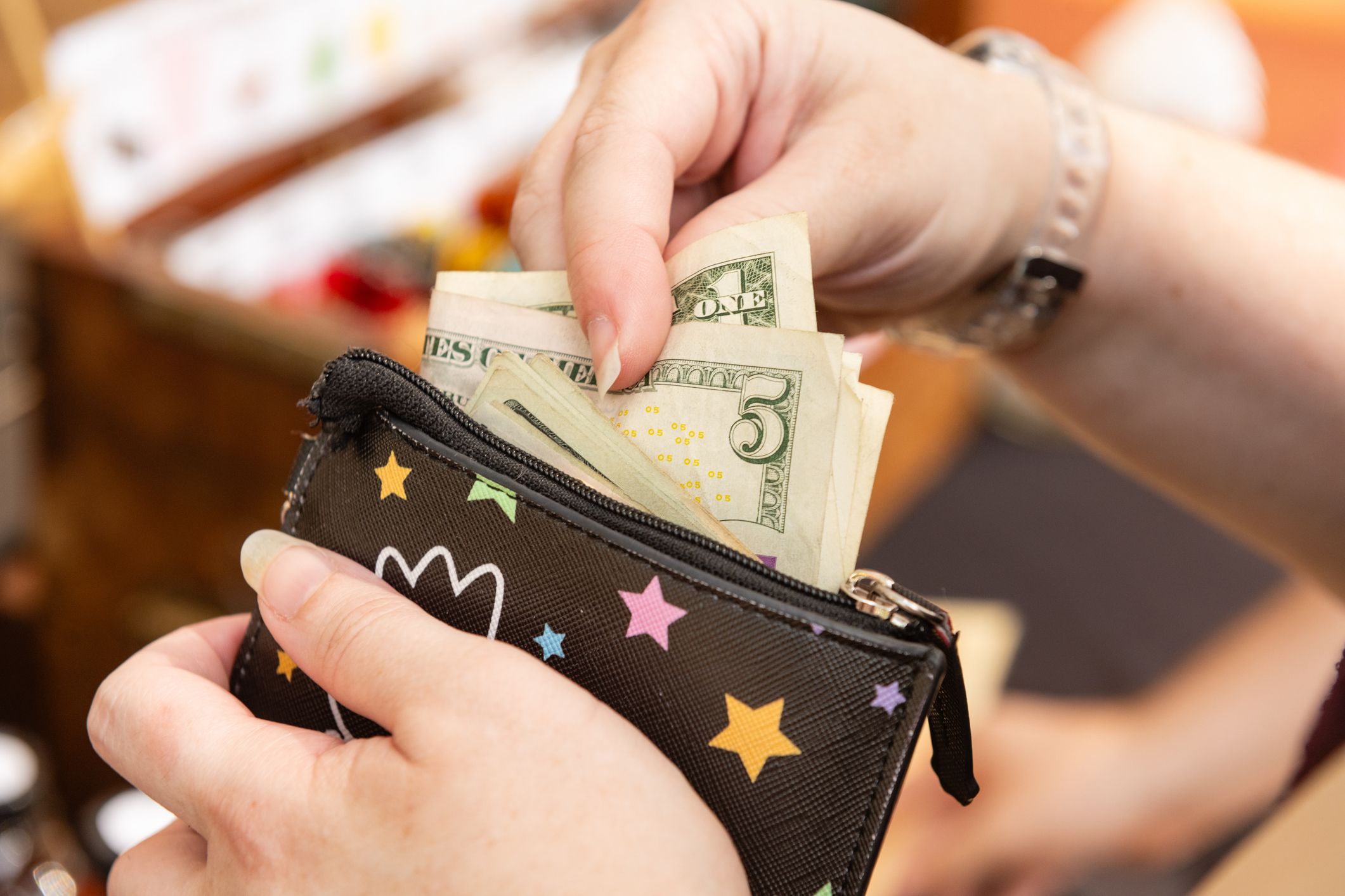 In Winter Garden, United States the Saturday Farmer’s Market a woman paying with cash pulls money out of a wallet.
