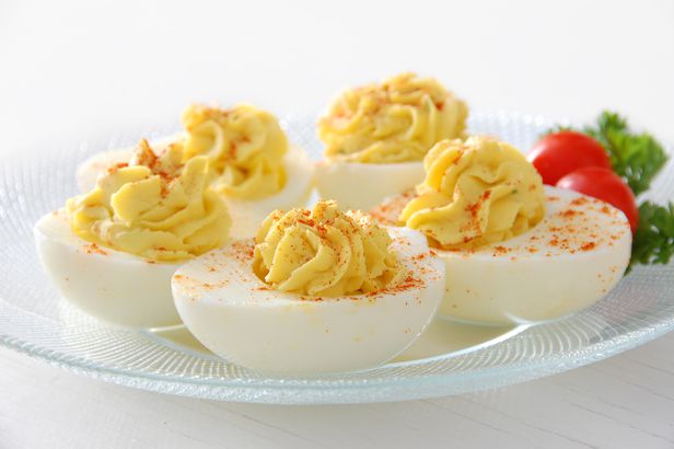 Deviled eggs served on clear plate with grape tomatoes
