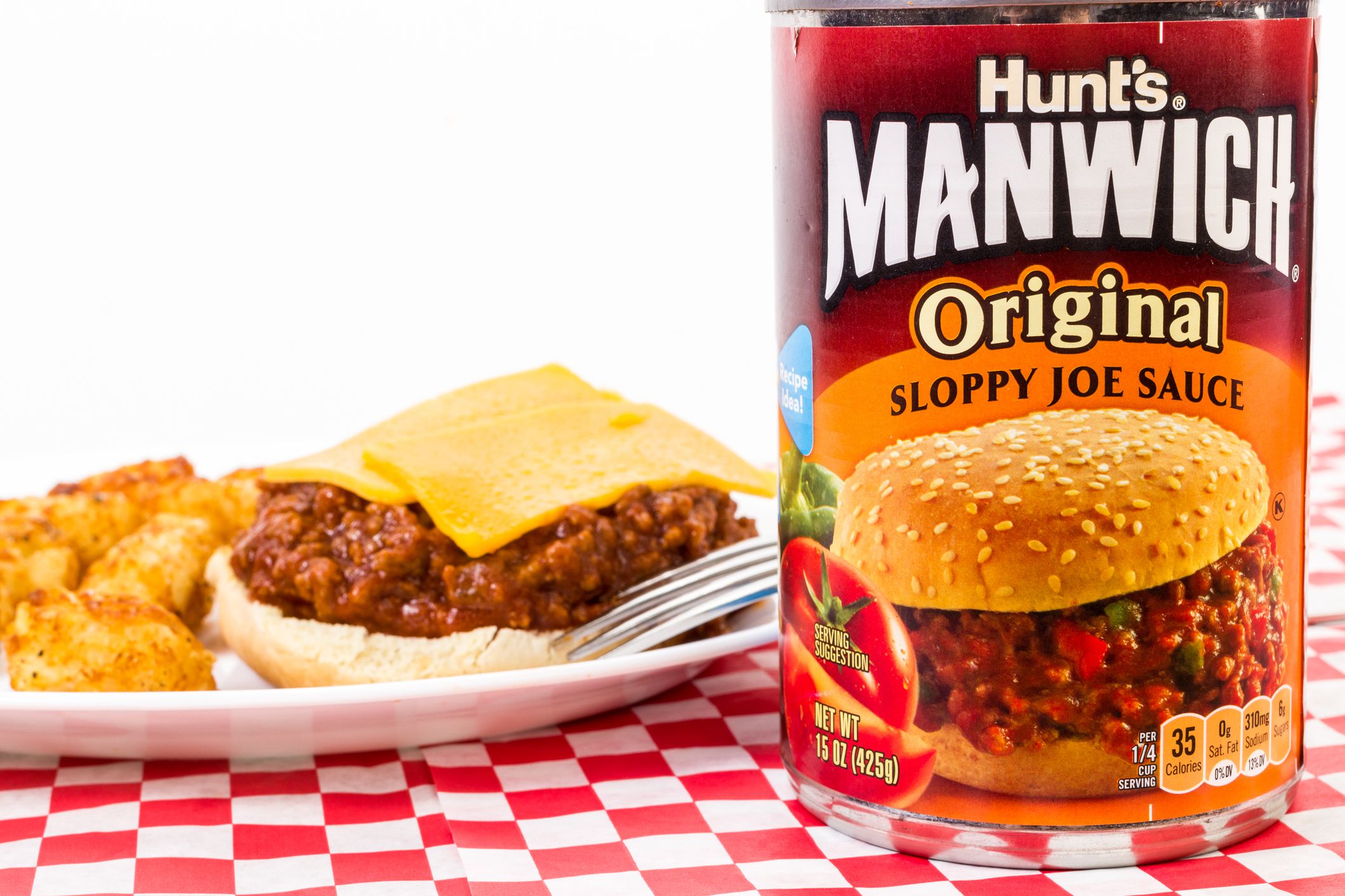 Llano, Tx, United States - January 5, 2016: Llano, Tx, United States - January 7, 2016: Can of Hunt's Manwich Original Sloppy Joe Sauce on red plaid table with sandwich on bun with cheese and deep-fried tater tots.