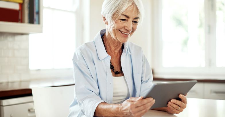 senior looking at tablet smiling