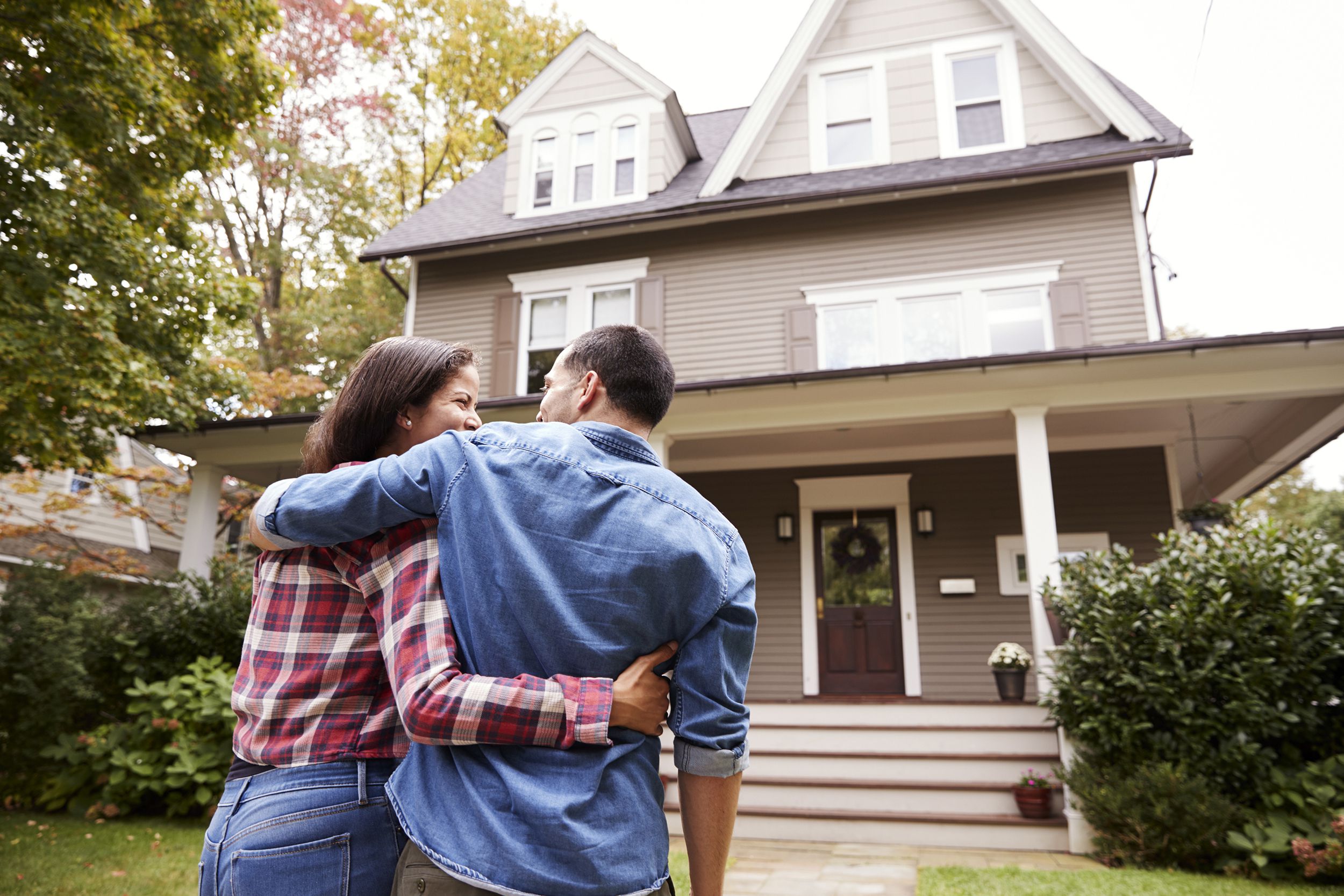 rear view of loving couple walking towards house