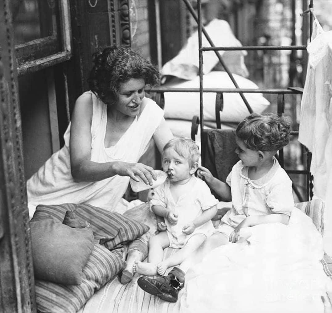 Mother and her children on a fire escape at 59 Norfolk Street, New York. In the dreadful heat of a New York summer, sleeping on the fire escape might be the only way to catch a breeze (1927)